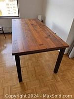 Full view of rectangular wood table with metal legs in a room, showing overall size and condition.