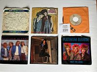 Top view of all 6 vinyl record covers and one 45 vinyl record disc visible. Shows front artwork of each record sleeve with diverse colors and images of artists.