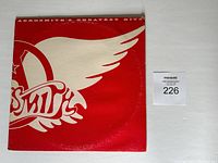 Front side of Aerosmith Greatest Hits LP album cover in red and white with winged logo.