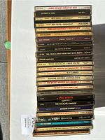 Front view of stacked CDs showing titles such as Janis Joplin's Greatest Hits, Bee Gees Greatest, and others.
