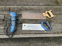 Photo showing the oscillating multi tool and two hand saws placed on wooden surface, clearly showing the brands and condition