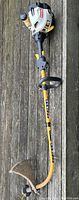 Full view of Ryobi CS26 string trimmer, showing curved shaft, engine housing, protective guard, and handle.