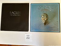 Two Eagles LP albums: 'The Long Run' with a black cover and 'Their Greatest Hits 1971-1975' with a blue cover showing the bird skull design.
