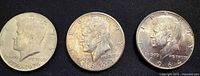 Obverse of three Kennedy Half Dollars (1776–1976, 1964, 1964)