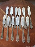 Twelve butter spreaders laid out showing full form