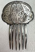 Front view of silver comb showing engraved floral design and overall form