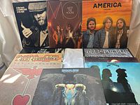 Group shot of nine visible record jackets showing artwork and titles, plus plain white sleeve partly visible