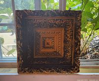 Front view of square relief artwork showing concentric carved design and coloration