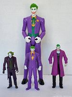 Four Joker action figures in various purple outfits, arranged in standing position showing front