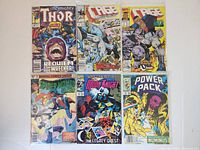 Photo showing 6 Marvel comic books including The Mighty Thor, Cage (two issues), Spider-Woman, Moon Knight, and Power Pack.