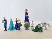 Front view of all nine Disney Frozen figures lined up, including two Annas, Elsa, Kristoff, Sven, Olaf, two trolls, and Marshmallow.