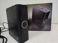 Black rectangular Western Digital My Book Essential Edition external hard drive standing upright in front of its original box.