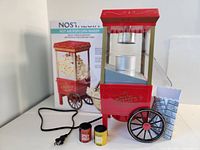 Front view of hot air popcorn maker with box, seasoning packets and popcorn bowl