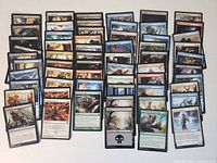Top-down image showing 60 Magic the Gathering cards laid out in rows, displaying front artwork and information on cards.