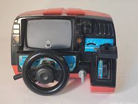 Front view showing steering wheel, dashboard with speedometer, buttons, and gear shift on electronic driving game.