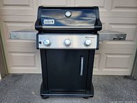 Front view of Weber Spirit gas grill showing lid, thermometer badge and three burner control knobs.