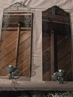 Front view of two mirrored wall sconces showing etched floral designs and metal candle holders