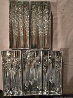 Five sets of clear plastic icicle Christmas ornaments in original boxes, arranged with two sets on top and three on bottom