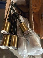 Semi-flush mount light fixture with 6 gold-tone cylindrical lamp heads on black adjustable arms, shown unpacked from box.