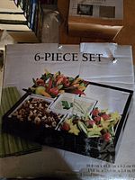 Photo of the 6 piece serving set box showing image of black wood tray with white ceramic sections filled with fruits and nuts