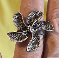 Close-up of the front face of the ring showing the five-petal flower design with textured petals and silver bead center.