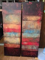 Front view of two tall abstract paintings side by side showing matched paired design with horizontal color bands and floral edges.