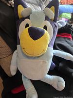 Front view of Bluey plush toy sitting upright with visible face and body details.