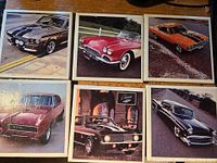 Six square photo coasters featuring images of classic cars in various colors arranged on a wooden surface.