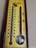 Close-up of the front plate showing the liquid-filled thermometer and weather prediction markers on a gold-tone backing.