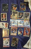Photo of approximately 18 Wayne Gretzky hockey cards arranged on a dark fabric background showing various card designs, brands, and conditions.