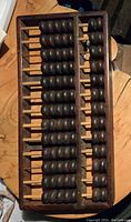 Top angle view of the full wooden abacus showing the rectangular frame and multiple rows of dark wooden beads.