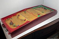 Angled view of the entire wooden tabletop hockey game showing the playing surface, player rods, and crocheted goal nets.