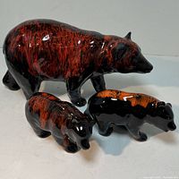 Three ceramic pottery bears shown together: one large and two smaller bears, all featuring black and reddish-brown glaze in mid-century modern style.