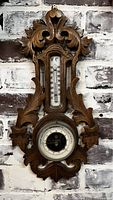 Full view of the ornate hand carved wooden barometer showing both thermometer and barometer sections