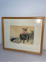 Framed antique Japanese print showing young farmer on water buffalo in traditional style.