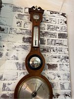 Full view of the tall mahogany barometer showing all components from the carved top to the circular dial at the bottom.