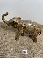 Side angle of the brass elephant sculpture showing detailed skin texture and raised trunk.