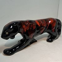 Side view showing prowling pose and red-black mottled glaze finish with crackle pattern.