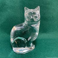 Front and side view showing smooth clear crystal, sitting cat shape with detailed facial features and curled tail.