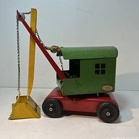 Side view showing red chassis, green operator cab and yellow boom with bucket extended