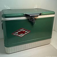 Side view of vintage green and white Coleman cooler with logo and latch