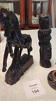 11.75 inch carved wooden horse figurine next to 10 inch stylized tribal woman carved bust, dark wood finish, carved with fine details on horse and woman.