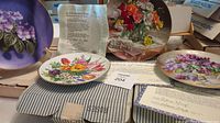 Set of four floral collector plates with original boxes and certificates showing different floral designs and packaging