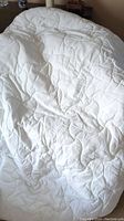 Full view of the white quilted mattress pad showing its stitched patterned surface and overall condition.