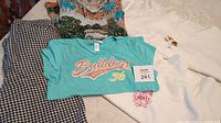 Overview of the lot showing the houndstooth leggings, teal Bulldogs tee, long sleeve woodland patterned top, and two white sweatshirts with embroidery.