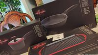 Hell's Kitchen branded packaging showing 9.5 inch non-stick frying pan, 1.5 quart saucepan with lid, and cast iron grill