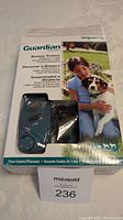 Photo of Guardian remote trainer device in original packaging showing remote and collar with branding and warranty info