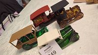 Four vintage Avon car bottles displayed on table, showing different car designs and colors including green, brown, red, and beige.