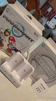 Photo of Mario Kart Wii game box with Wii Wheel, and Nyko charger in front of box