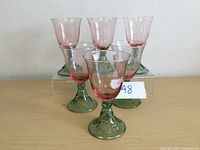 Image showing six pink goblets with green stems and bases arranged in a group, highlighting the whole set.